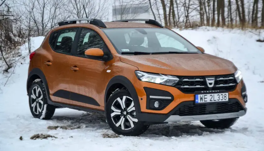 Pomarańczowy Dacia Sandero Stepway na śniegu, gotowy na zimowe wyzwania.
