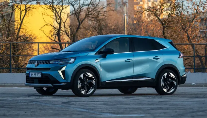 Niebieski Renault Symbioz na tle budynków i drzew. Wiele osób szuka o nim pozytywnych **renault symbioz opinie**.
