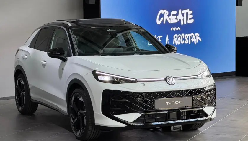 Biały Volkswagen T-Roc z czarnym dachem i felgami. Na ekranie w tle napis "CREATE LIKE A ROCSTAR". Sprawdź aktualną volkswagen t-roc cena.