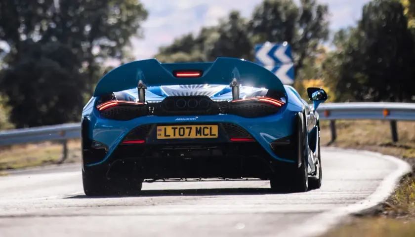 Niebieski McLaren 765LT z czterema końcówkami wydechu pędzi po zakręcie.