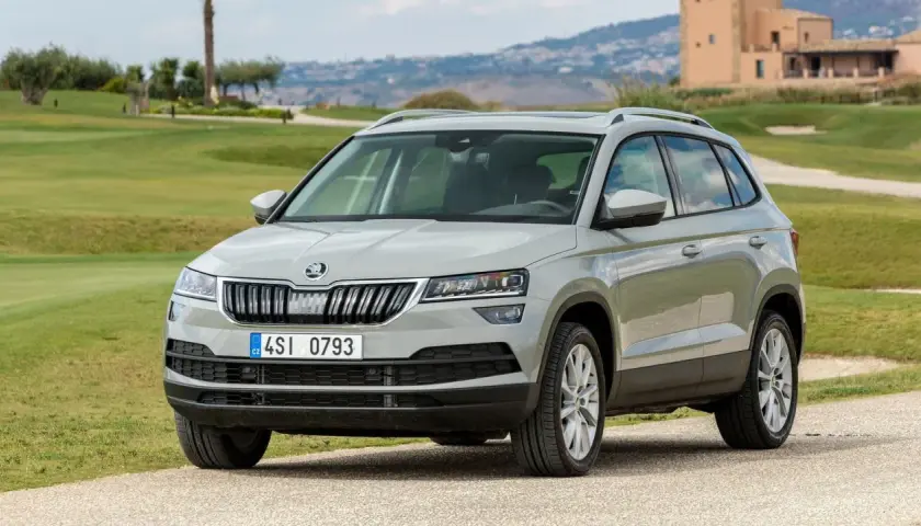 Szary Skoda Karoq na tle zielonych wzgórz. Wiele osób szuka skoda karoq opinie przed zakupem.