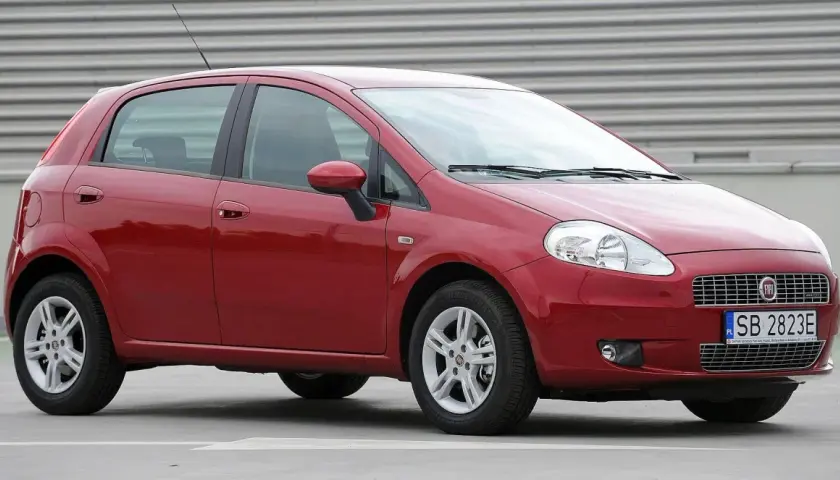 Czerwony Fiat Punto Grande z tablicą rejestracyjną SB 2823E zaparkowany na szarym podłożu.