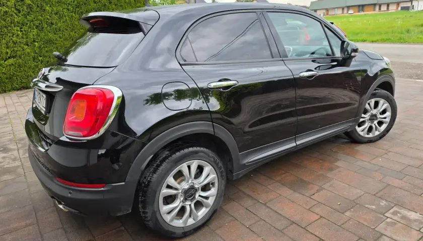 Czarny Fiat 500X widziany z boku, na brukowanym podjeździe.