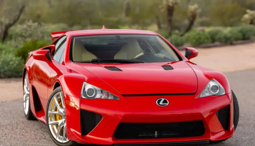 Czerwony Lexus LFA z żółtymi zaciskami hamulcowymi, zaparkowany na tle pustynnego krajobrazu.