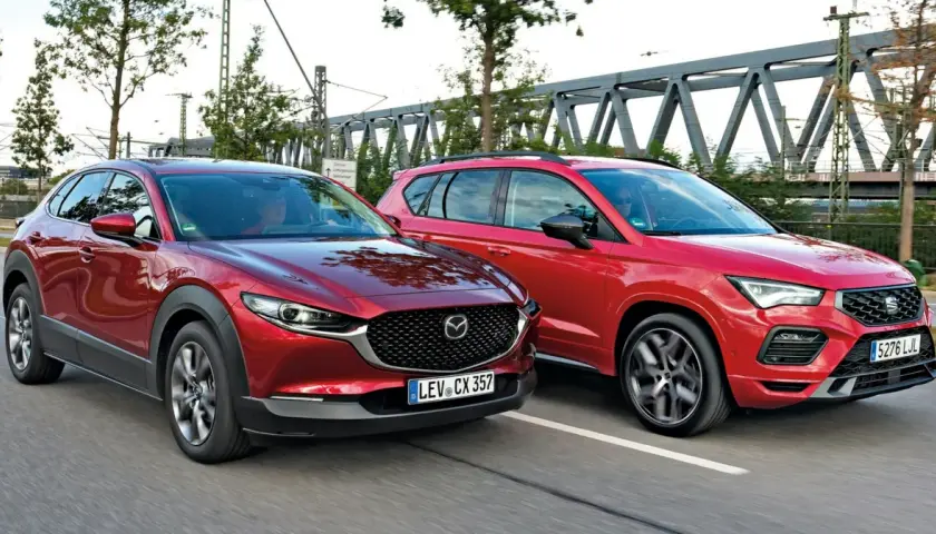Dwa czerwone SUV-y jadące obok siebie. Po lewej Mazda CX-30, po prawej Seat Ateca. Porównanie mazda cx 30 wymiary.