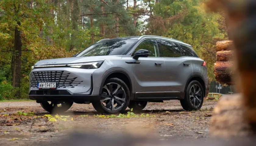 Srebrny SUV w lesie, gotowy na przygodę. Wiele pozytywnych baic 7 opinii potwierdza jego wszechstronność.