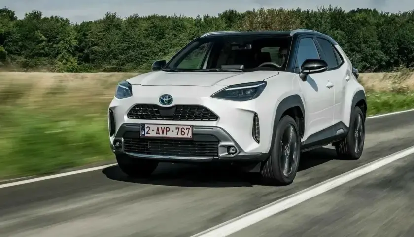 Biały Toyota Yaris Cross 2006 na drodze, z zielonymi drzewami w tle.