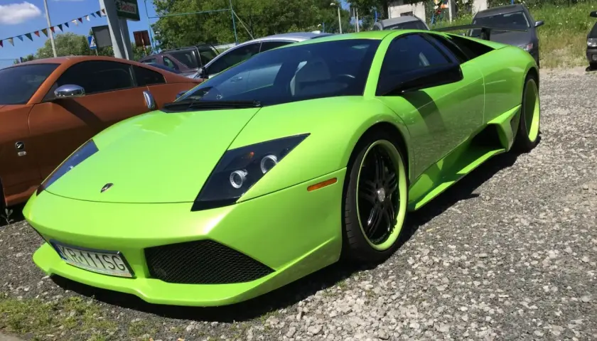 Jaskrawozielony Lamborghini Murcielago z czarnymi felgami i zielonymi akcentami stoi na żwirowym podjeździe.