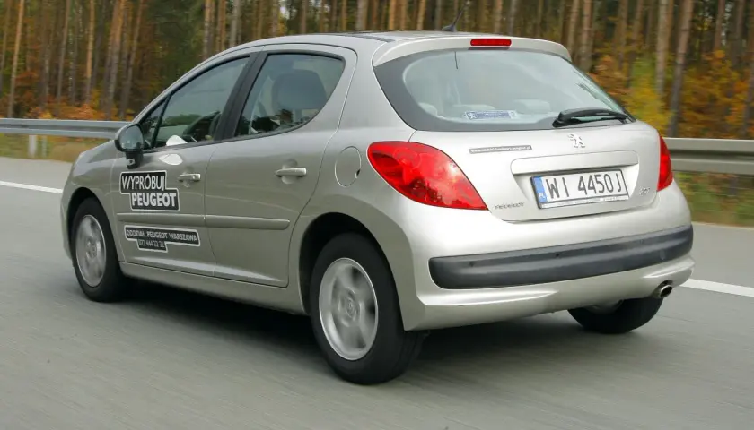 Srebrny Peugeot 207 1.4 benzyna w ruchu drogowym. Na drzwiach naklejka "Wypróbuj Peugeot".