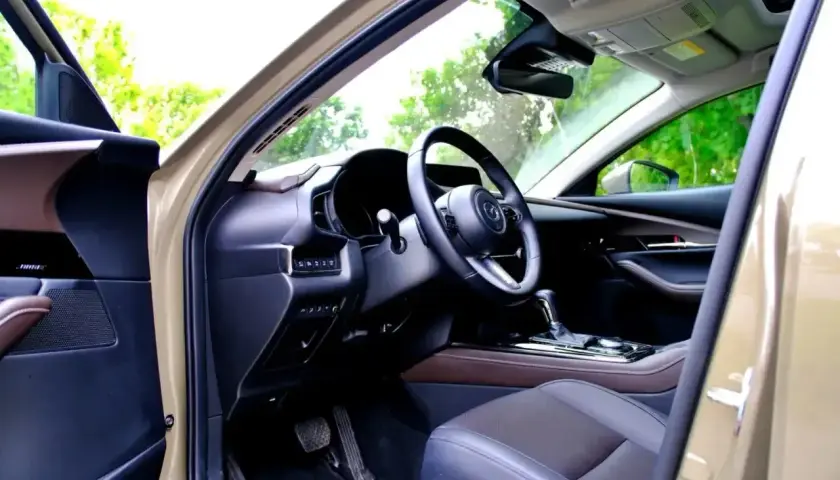Wnętrze Mazdy CX-30 z widokiem na deskę rozdzielczą, kierownicę i siedzenie.