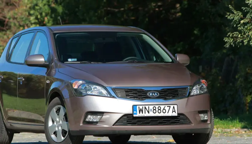 Brązowe Kia Ceed z przodu, na tle zieleni.