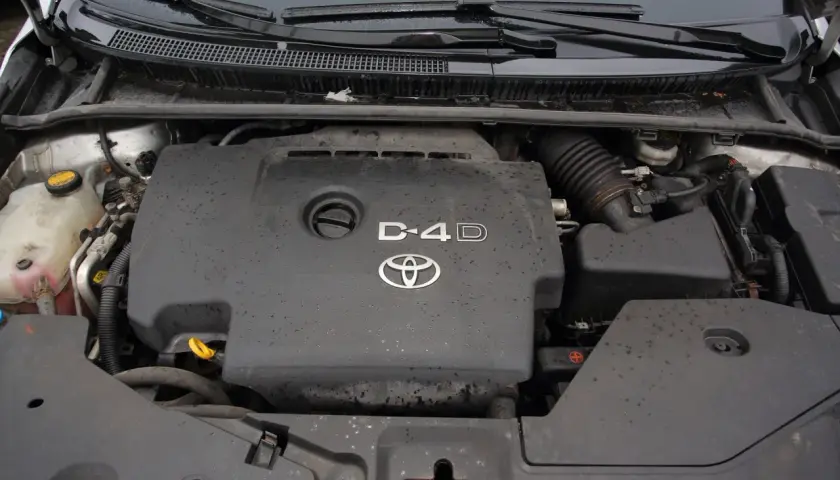 Silnik Toyota Avensis 2.0 D4D, widok z góry. Pokrywa silnika z logo Toyoty i oznaczeniem D4D.