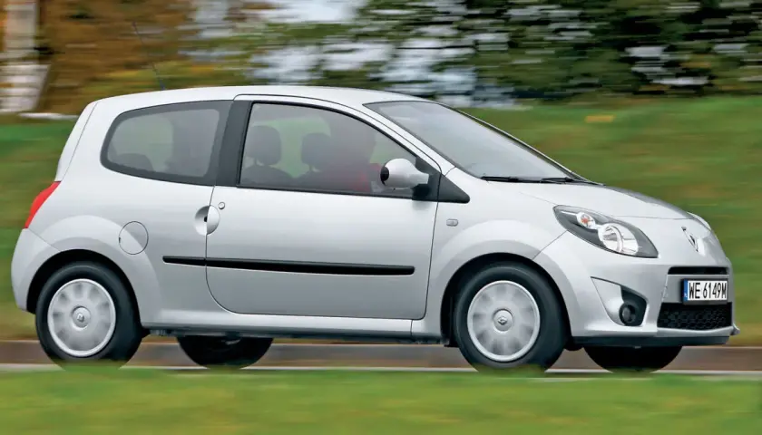 Srebrne Renault Twingo 2 w ruchu, z rozmazanym tłem zieleni i drzew.