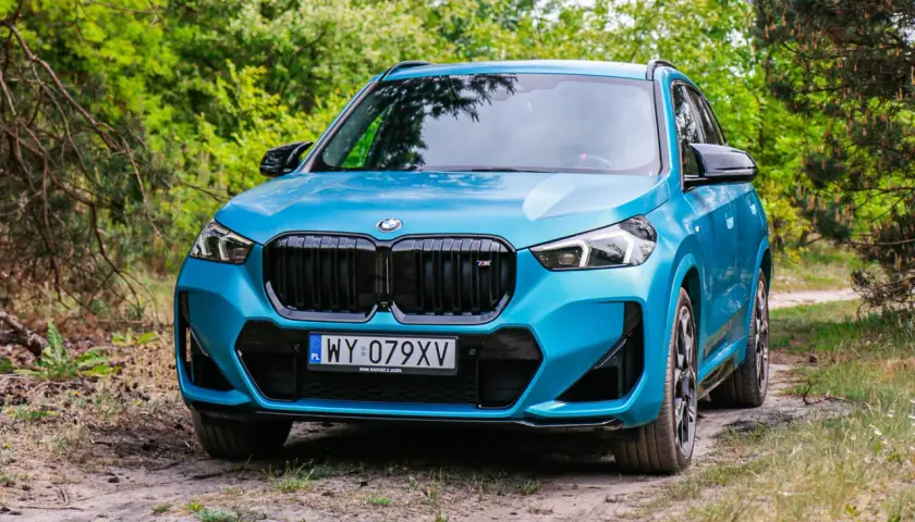 Niebieskie BMW X1 na leśnej drodze. Sprawdź jego kompaktowe bmw x1 wymiary, idealne do miasta i poza nim.