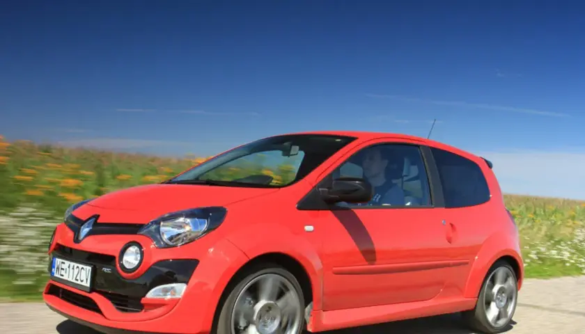 Czerwone Twingo RS pędzi przez kwitnące pola pod błękitnym niebem.