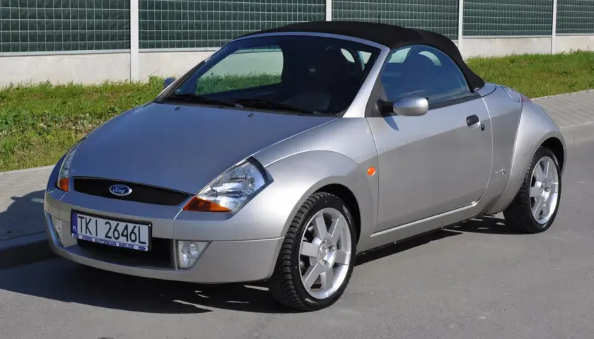 Srebrny Ford Streetka z czarnym dachem, zaparkowany na ulicy.