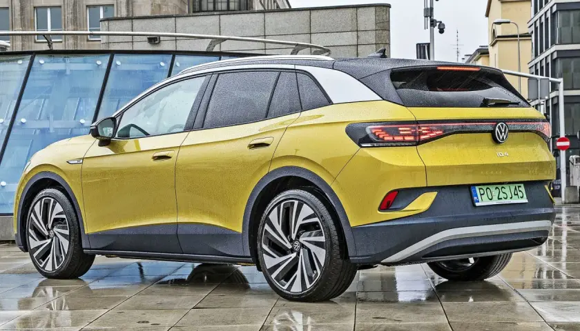 Żółty VW ID.4 z czarnym dachem i felgami stoi na mokrym chodniku.