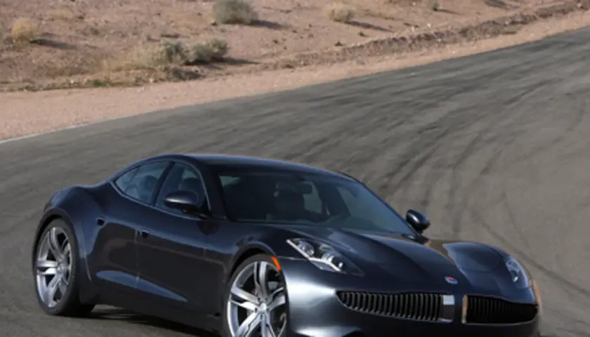 Elegancki, ciemny Fisker Karma na torze wyścigowym, gotowy do jazdy po pustynnych zakrętach.