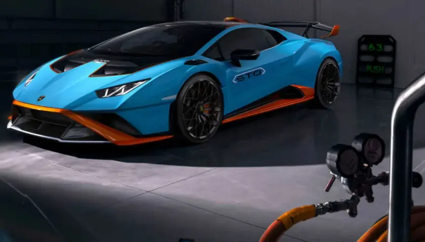 Niebieskie Lamborghini Huracán STO z pomarańczowymi akcentami w garażu.