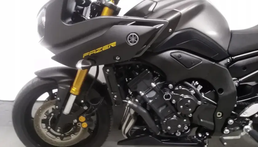 Ciemnoszary motocykl Yamaha FZ8 z żółtym napisem "FAZER" na owiewce. Widoczny przedni widelec i koło.