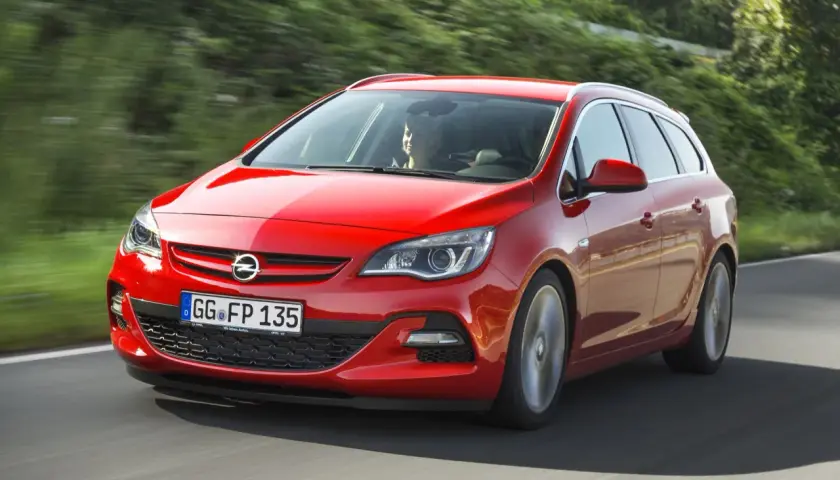 Czerwony Opel Astra J 1.4 Turbo 140 KM na drodze. Kierowca zadowolony, auto w ruchu.