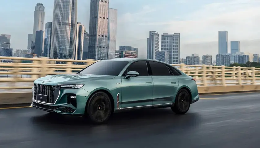 Elegancki, zielony Hongqi H9 jedzie po moście na tle drapaczy chmur. Sprawdź jego atrakcyjną hongqi h9 cenę!