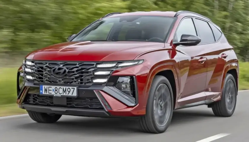 Czerwony Hyundai Tucson w ruchu drogowym. Zwróć uwagę na jego nowoczesny design i imponujące **hyundai tucson wymiary**, które zapewniają komfort i przestronność.