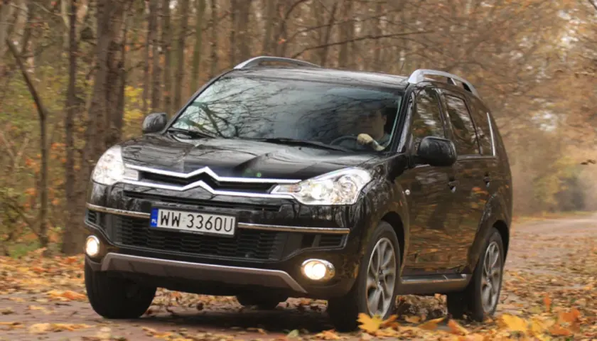 Czarny Citroën C-Crosser na drodze wśród jesiennych liści.