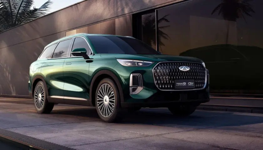 Elegancki, zielony Tiggo 9 Plug-in Hybrid prezentuje się stylowo na tle nowoczesnej architektury z palmami.