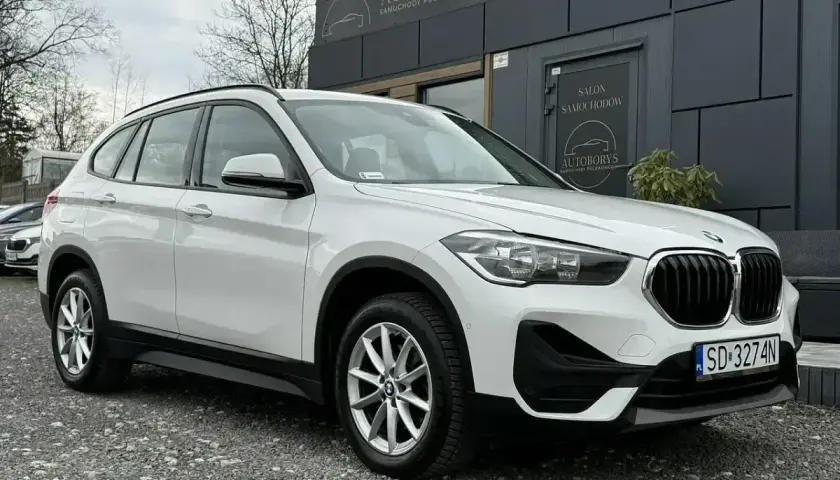 Białe BMW iX1 przed salonem samochodowym. Sprawdź atrakcyjną bmw ix1 cena!