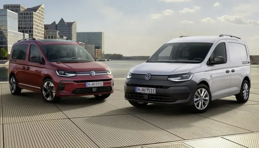 Dwa Volkswageny Caddy 3: czerwony osobowy i biały dostawczy, stoją na tle nowoczesnej architektury i wody.