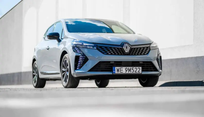 Nowoczesne Renault Clio 2024 w szarym kolorze prezentuje się dynamicznie na tle białej ściany.