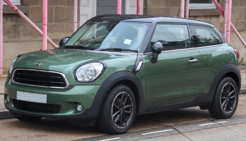 Zielony mini paceman stoi na ulicy, mokry od deszczu.
