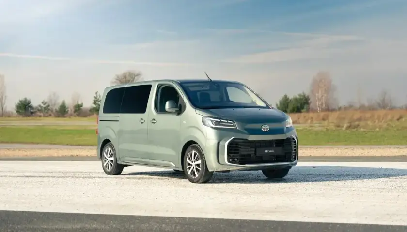 Nowy, zielony Toyota Proace na tle nieba i pól. Idealny do rodzinnych podróży i transportu.