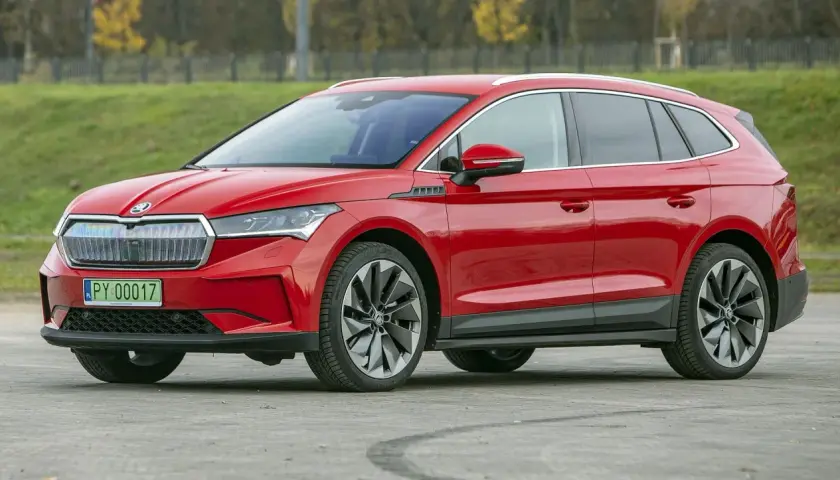 Czerwona Skoda Enyaq na tle zieleni. Sprawdź aktualną skoda enyaq cena i wybierz swój wymarzony samochód elektryczny.