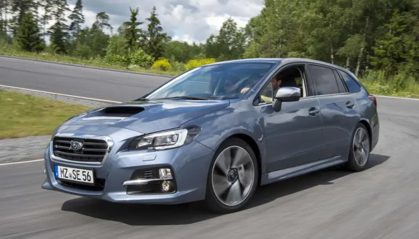 Szary Subaru Levorg na zakręcie drogi, otoczony zielenią.