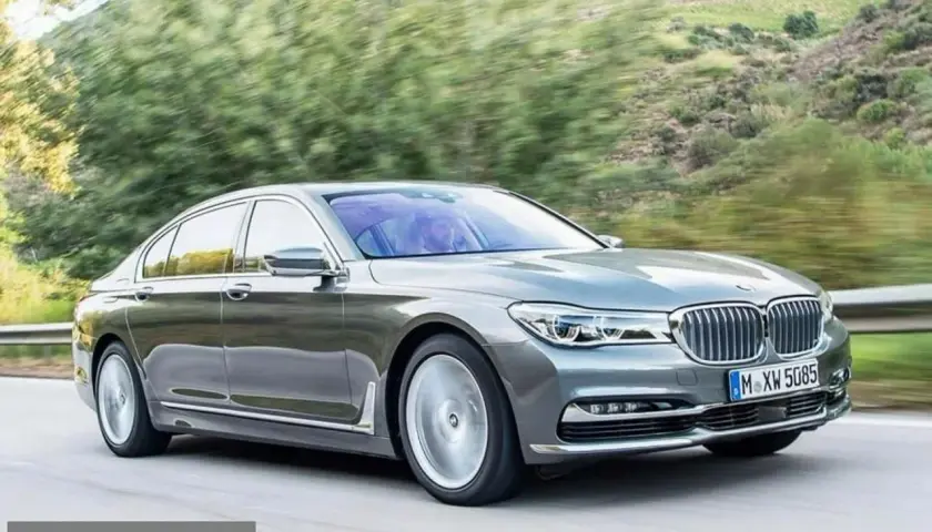 Eleganckie BMW 730d sunie po krętej drodze wśród zieleni.