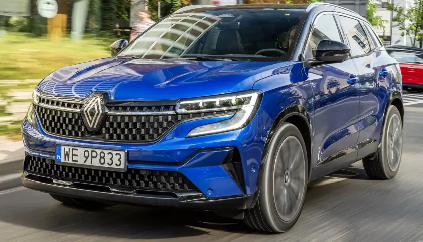 Błękitny Renault Austral pędzi po drodze, jego nowoczesny design i sportowy charakter przyciągają wzrok.