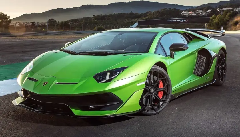 Jaskrawozielony Lamborghini Aventador SV na torze wyścigowym, z górami w tle.