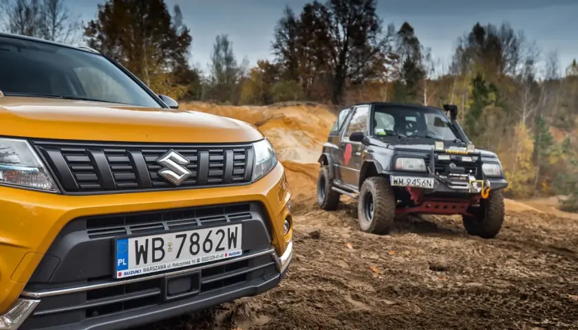 Żółty Suzuki Vitara 2025 i czarny, terenowy model na piaszczystym podjeździe.