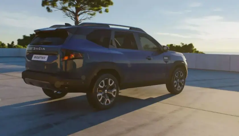 Niebieski Dacia Bigster na tle nieba i drzewa. Zbliżają się jego wymiary.