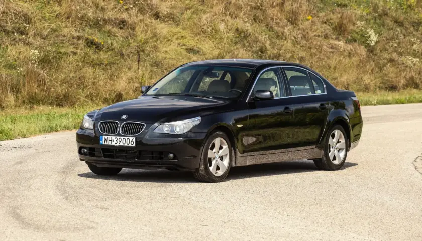 Czarne BMW 535d na tle zielonego wzgórza, gotowe na podróż.