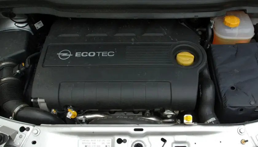 Silnik Ecotec w Oplu Zafira B. Widoczny czarny plastikowy dekiel z logo Opla i napisem Ecotec, żółty korek oleju i zbiorniczek płynu chłodniczego.