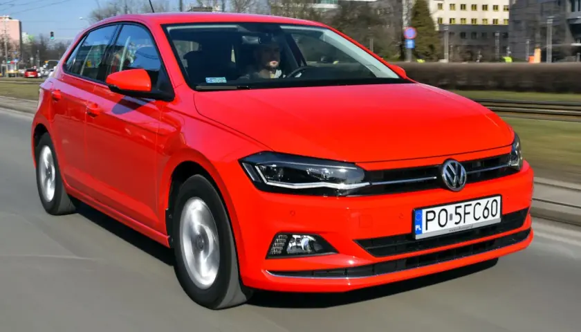 Czerwony Volkswagen Polo 6 w ruchu miejskim. Kierowca w szarej bluzie prowadzi auto.