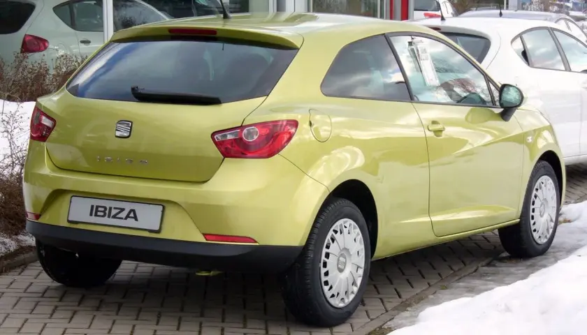 Żółty Seat Ibiza 1.4 benzyna z tyłu, zaparkowany na kostce brukowej.