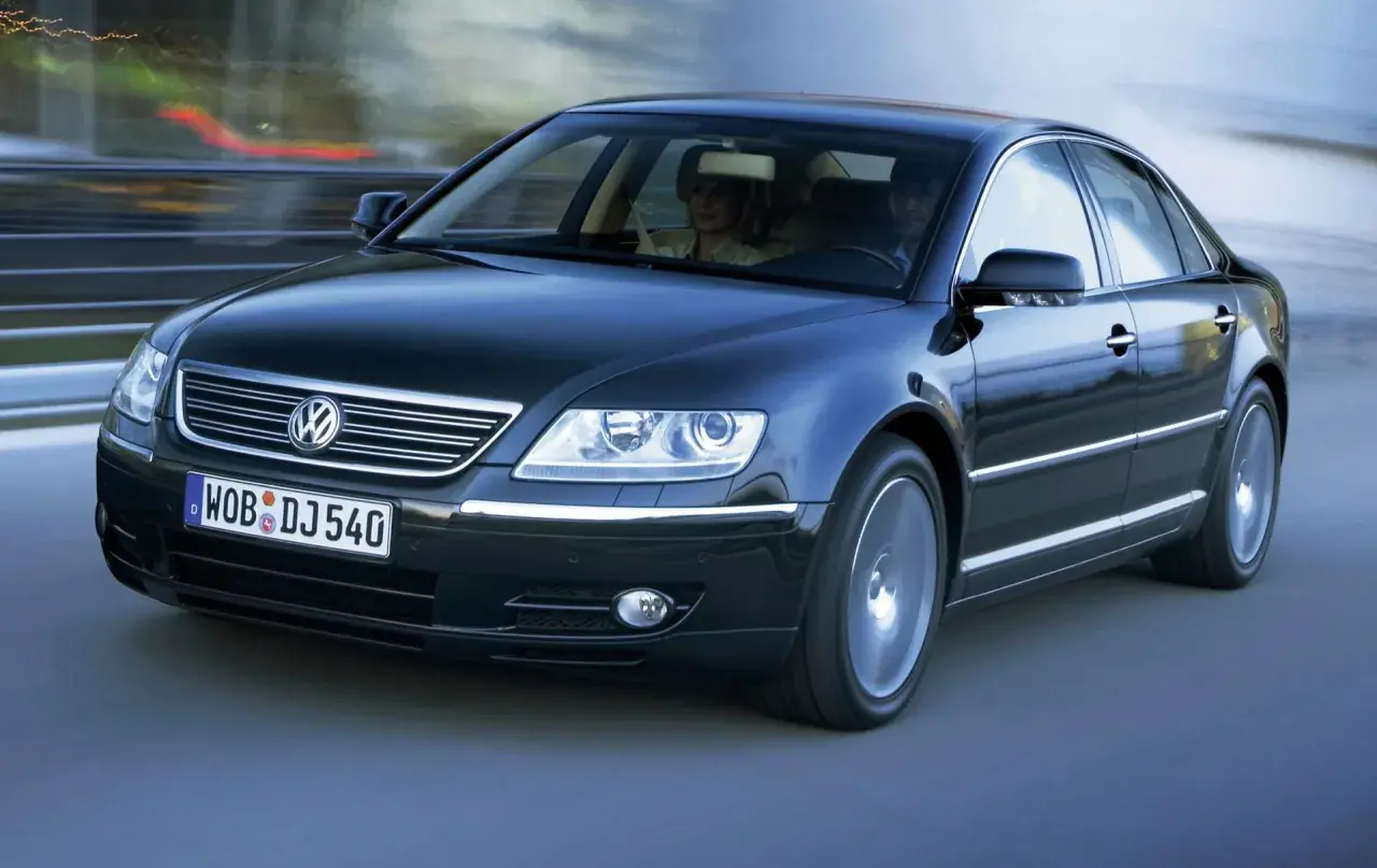 Elegancki, czarny Volkswagen Phaeton w ruchu, z parą pasażerów w środku.