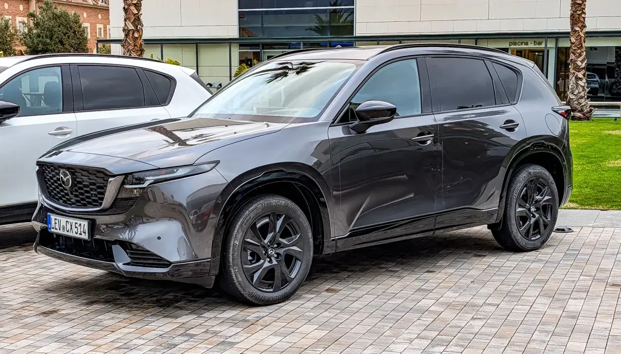 Ciemnoszara Mazda CX-5 na czarnych felgach, gotowa do jazdy. Wiele osób chwali ten model, a opinie o Mazda CX-5 są zazwyczaj pozytywne.