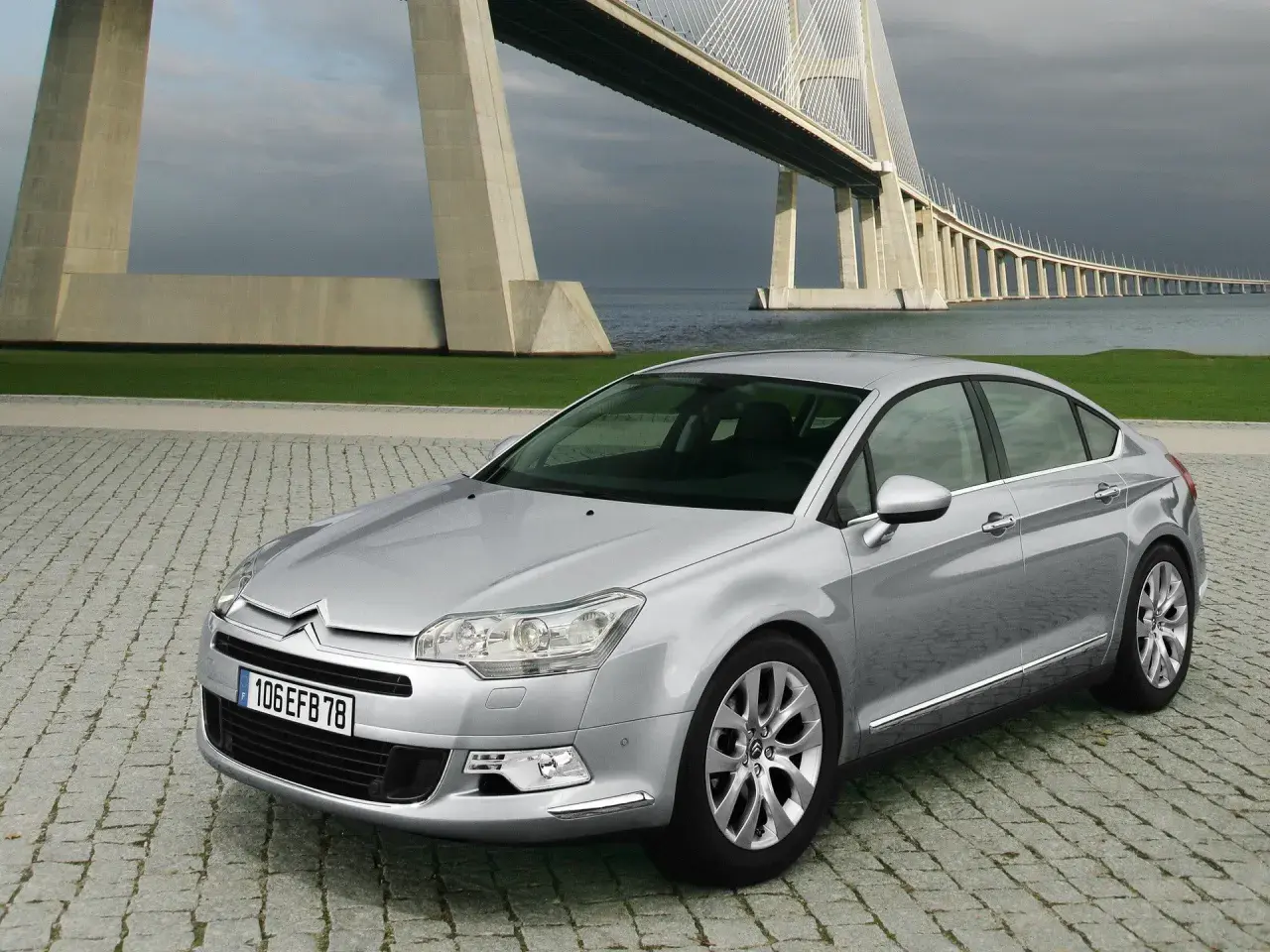 Srebrny Citroen C5 2.0 HDI na tle imponującego mostu wiszącego.