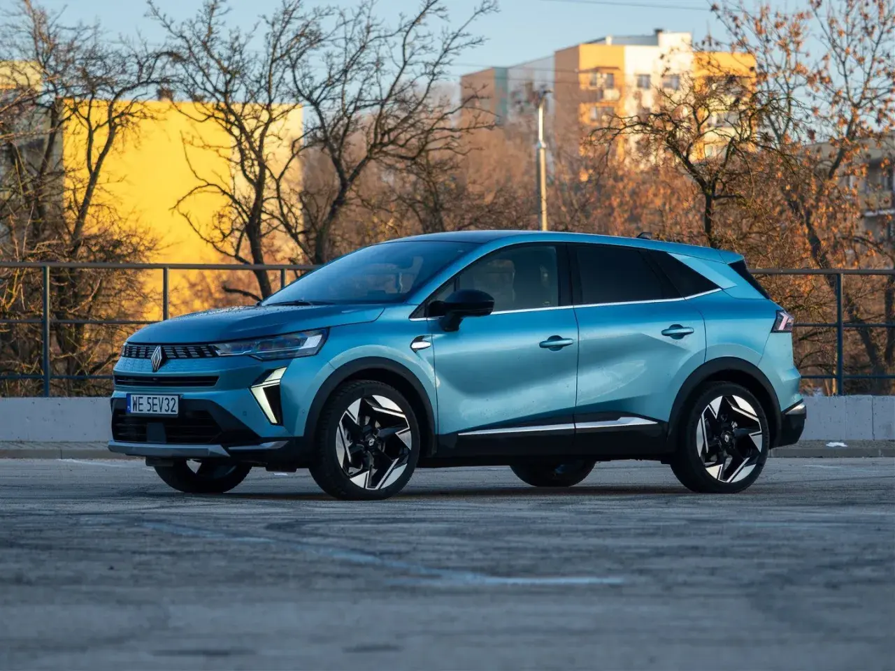 Niebieski Renault Symbioz na tle budynków i drzew. Wiele osób szuka o nim pozytywnych **renault symbioz opinie**.