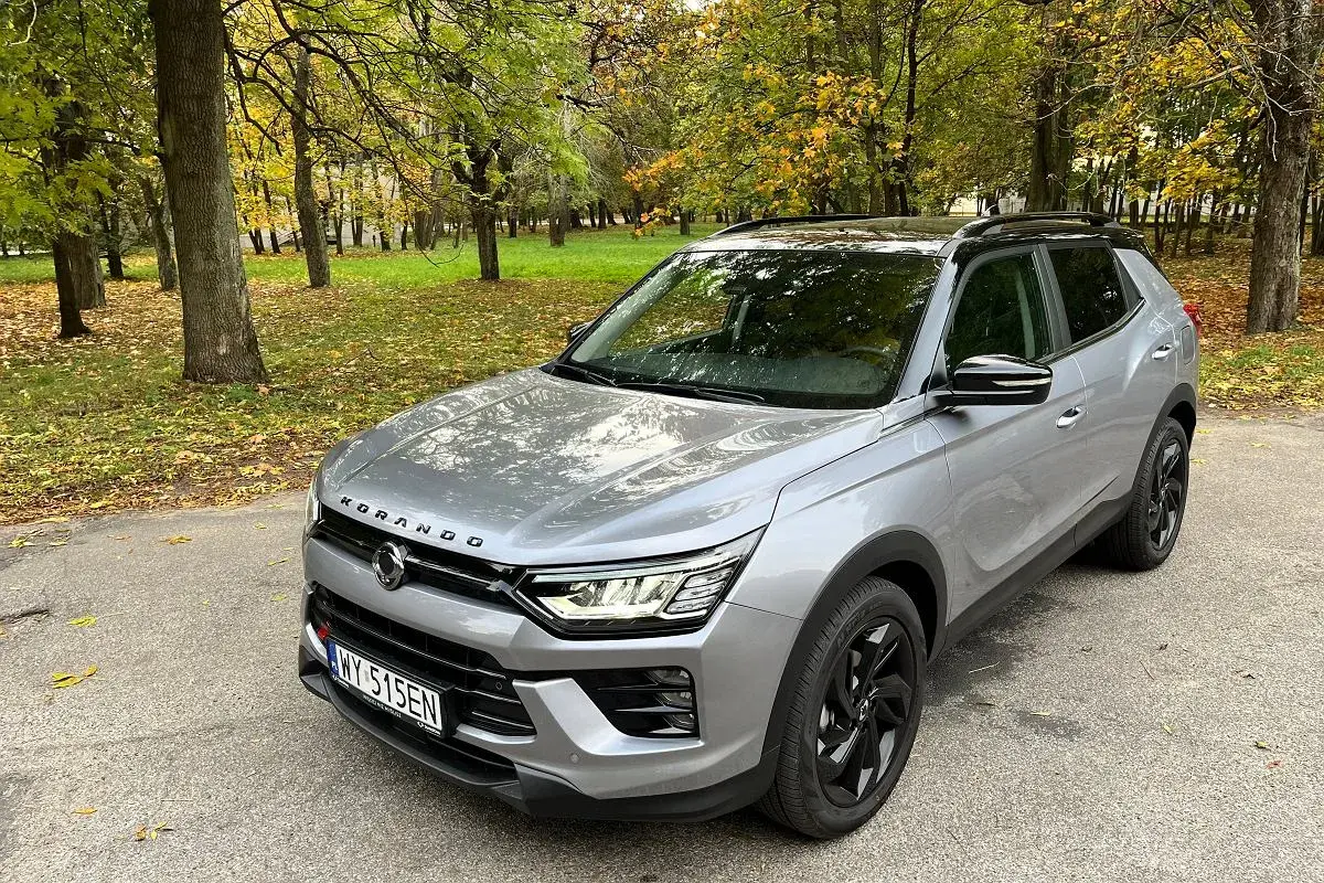 Srebrny SsangYong Korando na tle jesiennego parku. Wiele pozytywnych ssangyong korando - opinie użytkowników potwierdza jego wszechstronność.